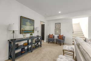 Living area with recessed lighting, light carpet, and stairway