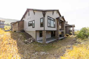 Back of house featuring a patio area and stone siding