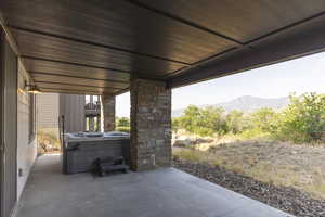 View of patio with a hot tub and a mountain view