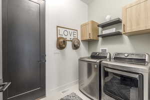 Laundry room with cabinet space, washer and clothes dryer, and light tile patterned floors