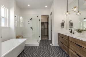 Full bath featuring a shower stall, a freestanding bath, double vanity, tile patterned flooring, and recessed lighting
