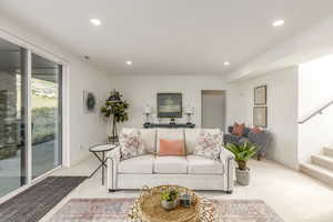 Living area featuring recessed lighting, stairs, and light carpet