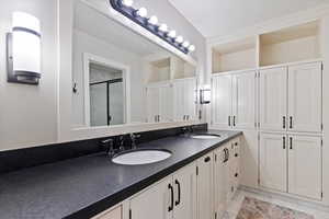 Full bath with double vanity and a shower with door