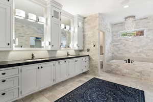 Full bath with tile walls, double vanity, a garden tub, tasteful backsplash, and recessed lighting