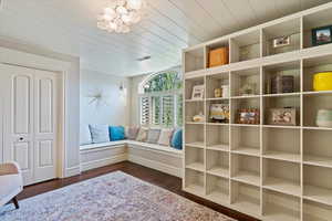 Living area with dark wood finished floors, a chandelier, and wooden ceiling