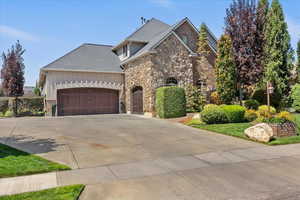 Craftsman house featuring a garage, stone siding, driveway, and roof with shingles