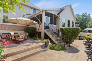 Back of house with a patio area, a sunroom, stairway, and a shingled roof