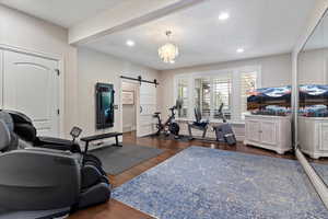 Workout room featuring a barn door, wood finished floors, a chandelier, and recessed lighting