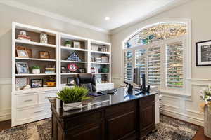 Office space with a decorative wall, a wainscoted wall, crown molding, and dark wood-type flooring