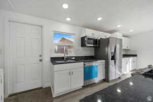 Kitchen with backsplash, appliances with stainless steel finishes, dark stone countertops, and recessed lighting