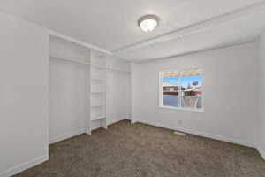 Unfurnished bedroom featuring dark carpet and a closet