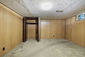 Finished basement featuring carpet floors, wooden walls, and a textured ceiling