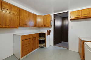 Kitchen with brown cabinetry, light countertops, and concrete flooring