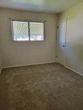 Carpeted spare room featuring baseboards