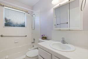 Bathroom with bathing tub / shower combination, vanity, and tasteful backsplash