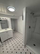 Bathroom featuring vanity, a stall shower, and light floors
