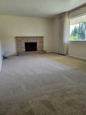 Unfurnished living room with carpet floors and a stone fireplace