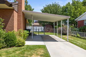 View of parking / parking lot featuring a storage unit, a carport, and driveway