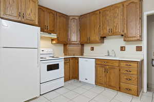 Kitchen with white appliances, brown cabinets, and light tile patterned floors