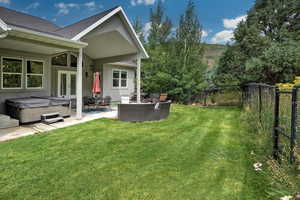 Back of property with a hot tub, a fenced backyard, a patio area, a shingled roof, and stucco siding