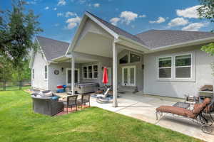 Back of house with roof with shingles, a hot tub, stucco siding, french doors, and an outdoor living space