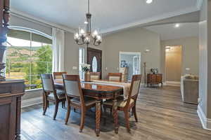 Dining room featuring light wood-style flooring, ornamental molding, a chandelier, lofted ceiling, and recessed lighting