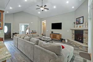 Living room with high vaulted ceiling, a fireplace, wood finished floors, a ceiling fan, and recessed lighting