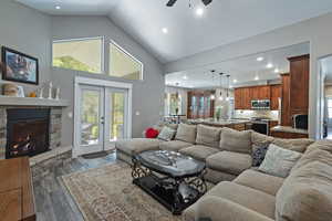 Living area with high vaulted ceiling, a stone fireplace, recessed lighting, dark wood-style flooring, and a ceiling fan