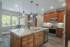 Kitchen with tasteful backsplash, appliances with stainless steel finishes, dark wood finished floors, recessed lighting, and decorative light fixtures