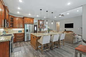 Kitchen featuring open floor plan, tasteful backsplash, stainless steel appliances, a breakfast bar, and dark wood finished floors