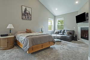 Bedroom with lofted ceiling, carpet flooring, a tiled fireplace, and recessed lighting