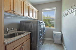 Washroom featuring washing machine and clothes dryer, cabinet space, and light tile patterned floors
