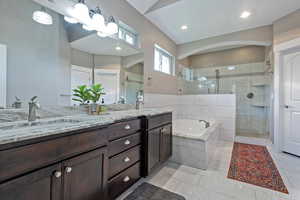 Bathroom featuring double vanity, a shower stall, and a garden tub