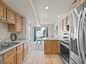 Kitchen with appliances with stainless steel finishes, a peninsula, light wood finished floors, recessed lighting, and light countertops