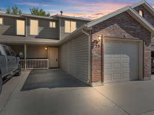 Traditional home featuring driveway, a garage, brick siding, and stone siding