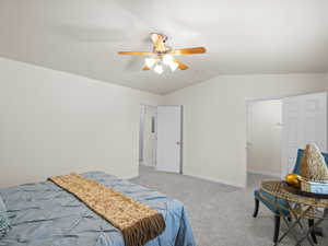 Bedroom with lofted ceiling, light carpet, ceiling fan, and a spacious closet