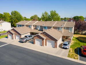 View of front of house featuring brick siding, a residential view, a garage, and a shingled roof