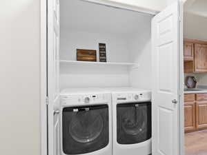 Laundry room with independent washer and dryer and light wood finished floors