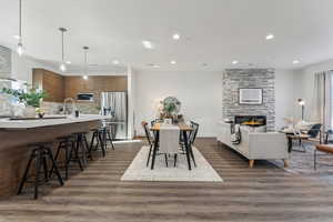 Dining area featuring dark wood-type flooring, a stone fireplace, recessed lighting, and healthy amount of natural light
