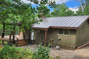 Back of property featuring a wooden deck, a standing seam roof, a metal roof, and a chimney