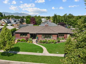 View of front of property with a front lawn, stately brick, the neighborhood park-like view, with mountains in the distance