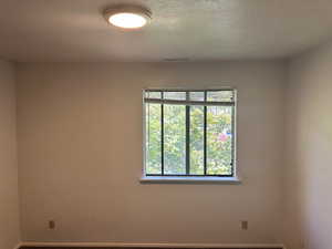 Unfurnished room with a textured ceiling and baseboards