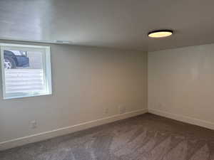 Unfurnished room featuring dark carpet and baseboards