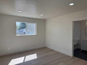 Unfurnished bedroom with recessed lighting, light wood-style flooring, and ensuite bath
