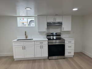Kitchen featuring electric stove, light countertops, light wood-type flooring, white cabinetry, and recessed lighting