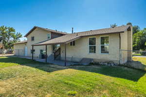 Rear view of property featuring brick siding, a shingled roof, a patio, and a chimney