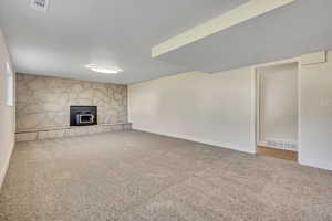 Unfurnished living room with carpet floors and a wood stove