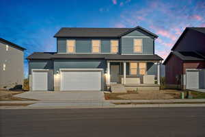 Traditional-style house with a porch, concrete driveway, and an attached garage