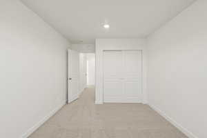 Unfurnished bedroom featuring light carpet, a closet, and recessed lighting