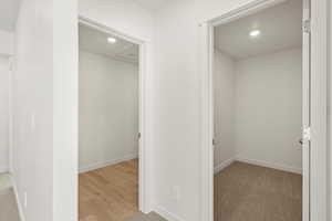 Hallway with light colored carpet, recessed lighting, and light wood-style flooring